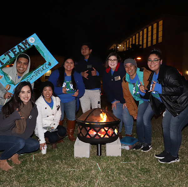 Students gather around a bondfire for Islander Peer Educatorsevent at night