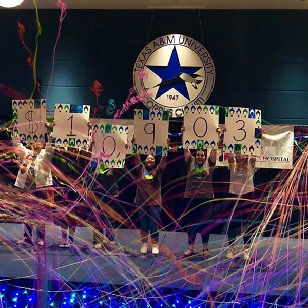 Students holding up individual signs saying that there was over $10,000 raised at dance marathon