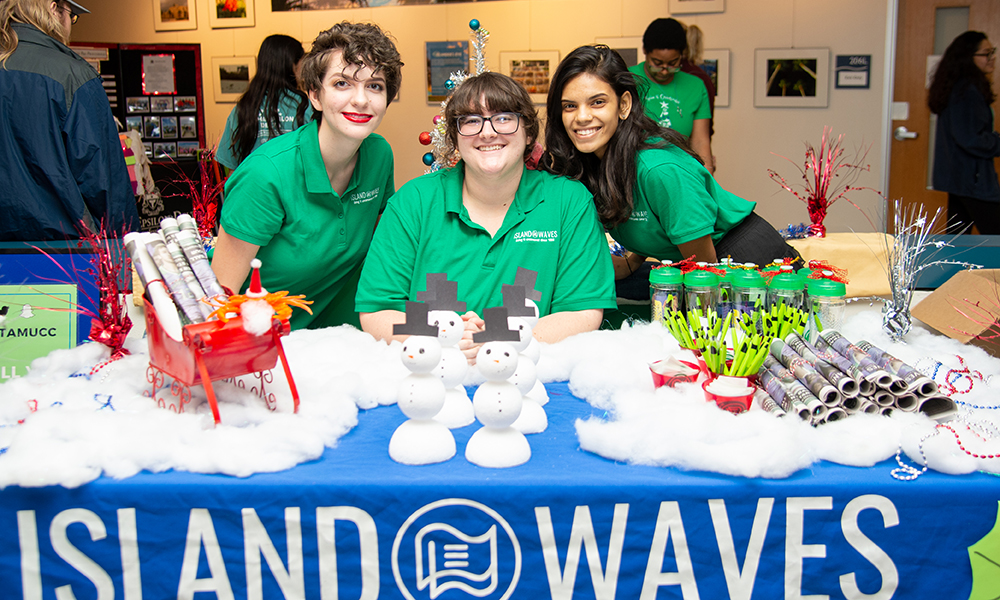 3 students at an Islander Waves Village table